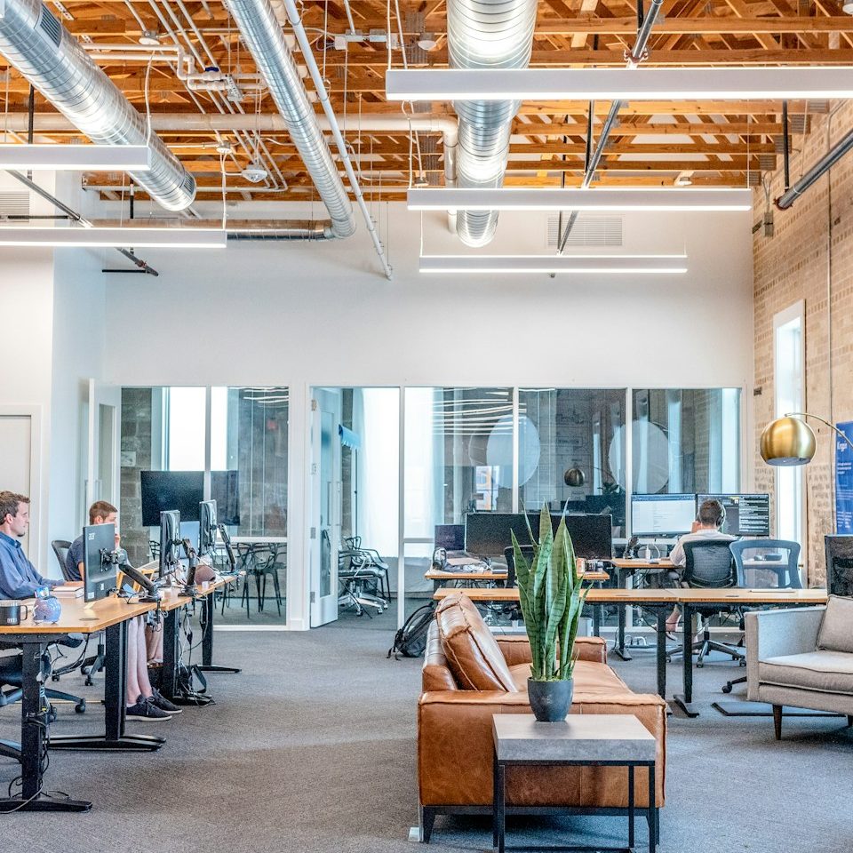 Modern office interior with open layout, desks, and plants. Bright and well-lit space.